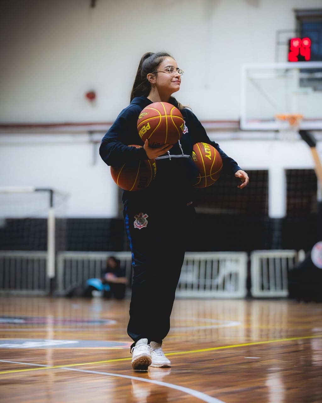 Joana Paiva cruza la cancha llevando tres balones de baloncesto antes del entrenamiento.